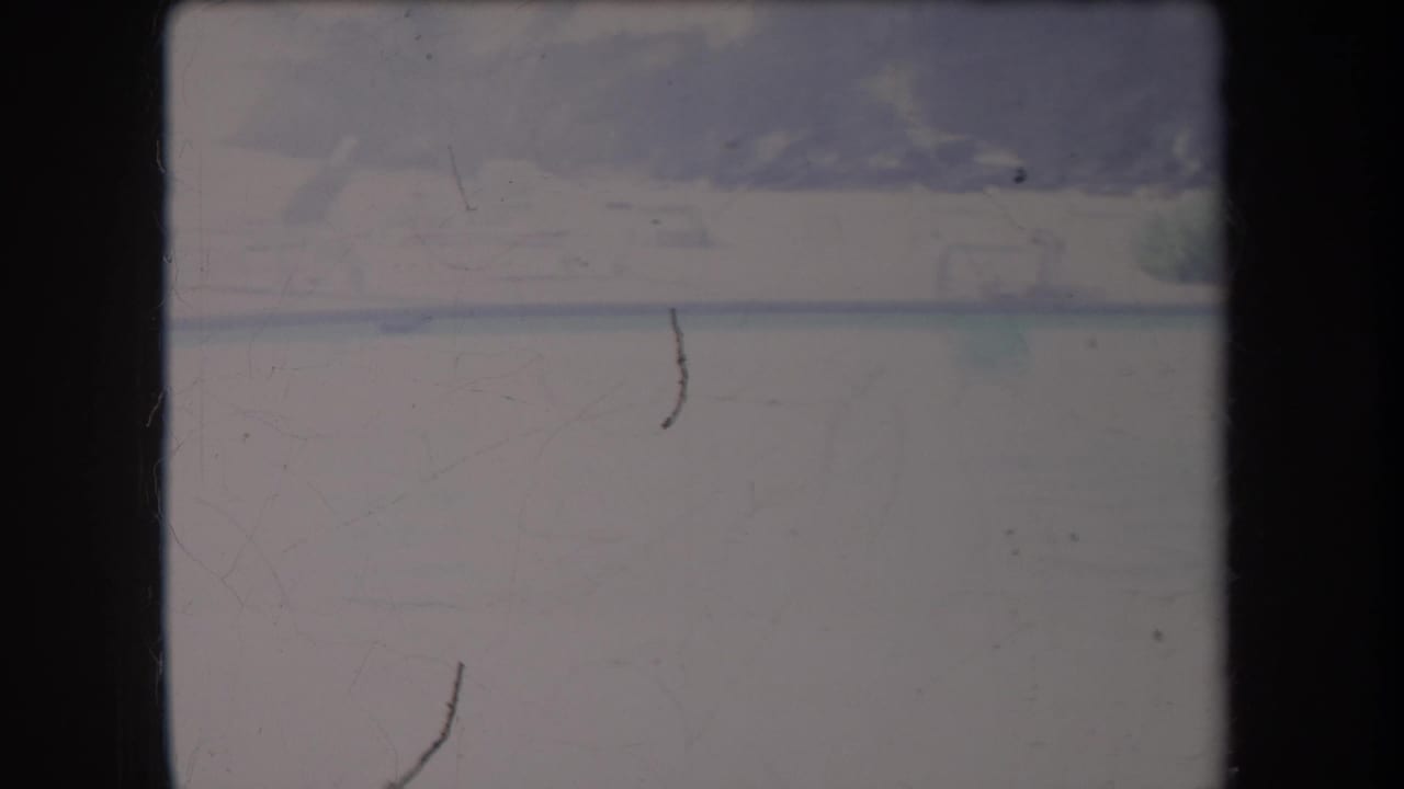 Overexposed foggy water with faint shoreline and dark film edges.
