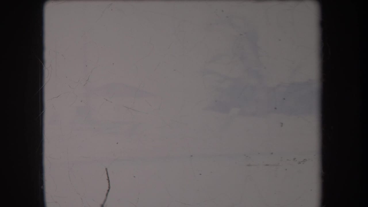 Faded 8mm frame from the Hawaii 1969 clip, showing a largely overexposed outdoor view with scratches and dark gate edges.