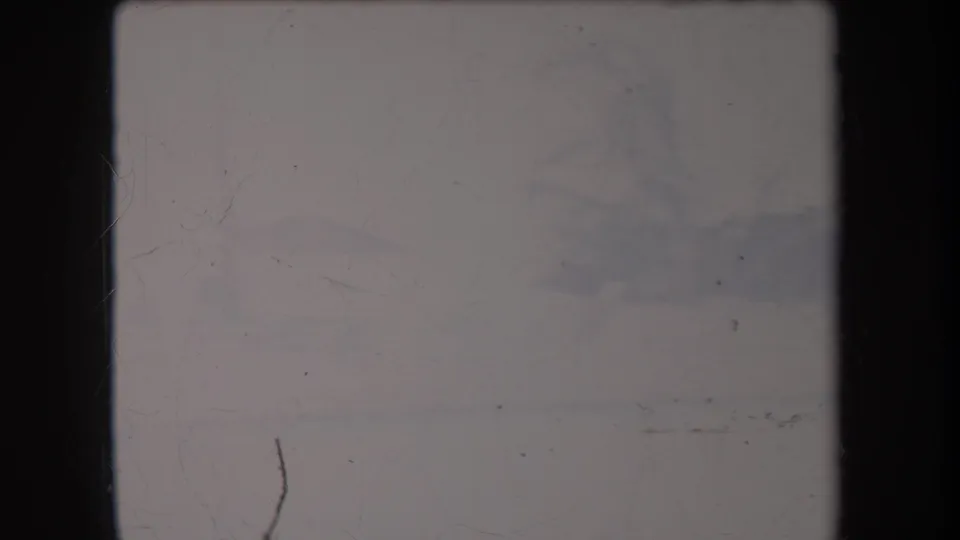 Faded 8mm frame from the Hawaii 1969 clip, showing a largely overexposed outdoor view with scratches and dark gate edges.