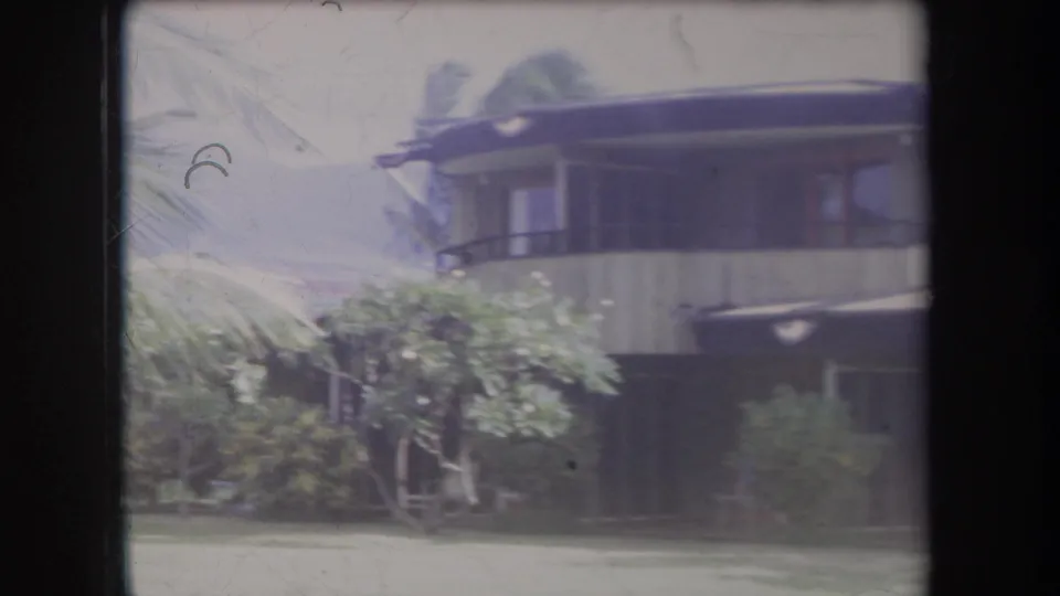 1969 Hawaii 8mm frame showing a residential exterior, balcony area, lawn, and tropical foliage.