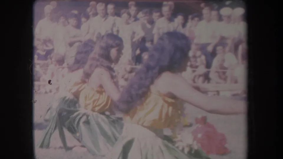 Soft 8mm Hawaii frame from 1969 showing two women dancing side by side with a public audience behind them.