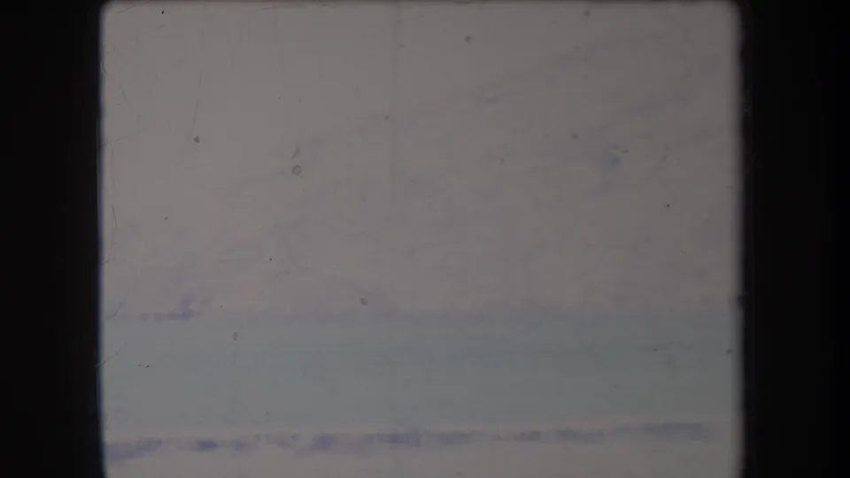 1969 Hawaii 8mm frame showing a soft, distant snowy mountain or ridge above a pale flat foreground.
