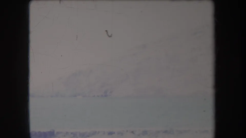 1969 Hawaii 8mm view of a distant snow-covered ridge or mountain line, softened by haze and film wear.