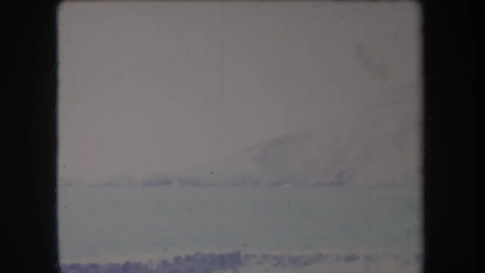 1969 Hawaii 8mm frame with a low, hazy mountain form beyond a broad pale snow or ice foreground.