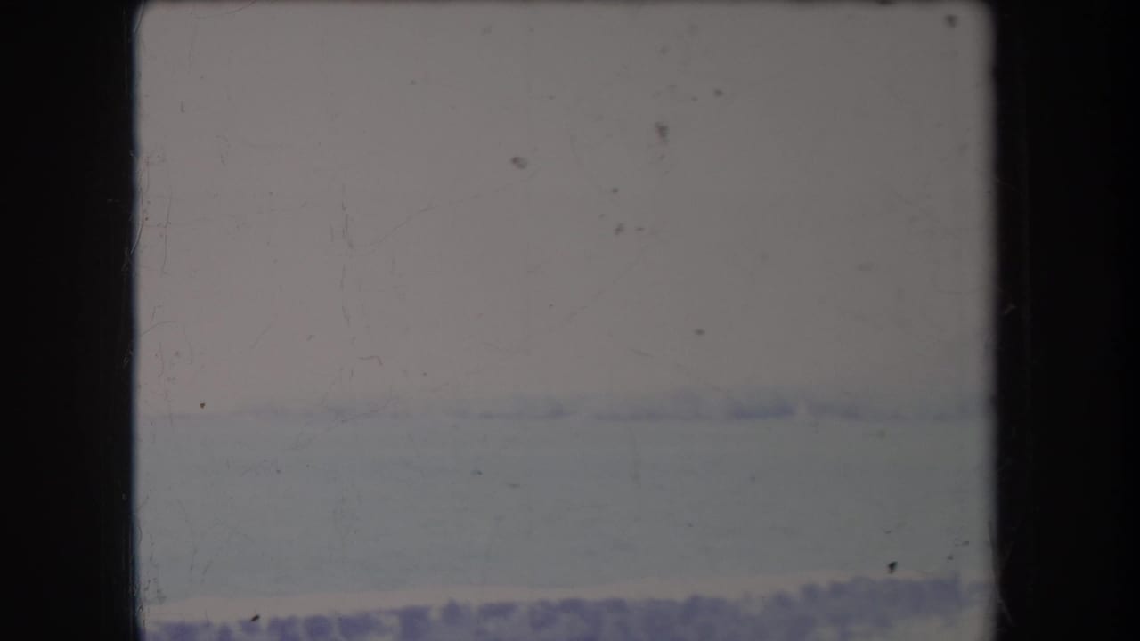 Hazy 1969 Hawaii 8mm frame showing a pale ocean horizon and sky with heavy overexposure and film marks.