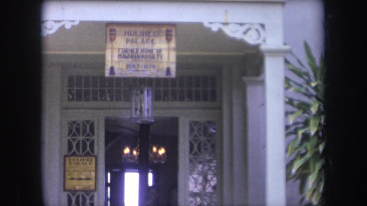 Hulihee Palace entrance with white columns, signage, lattice panels, and open doorway.