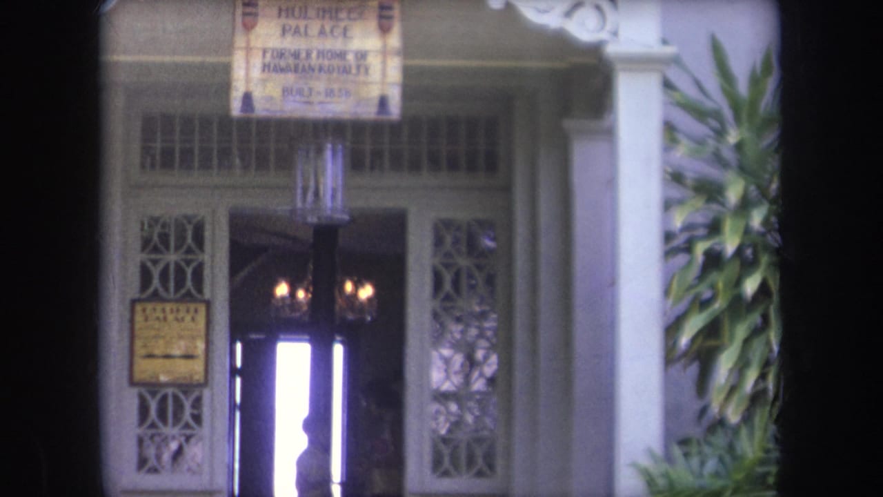 Closer view of the palace doorway with hanging signs, columns, and interior lights.