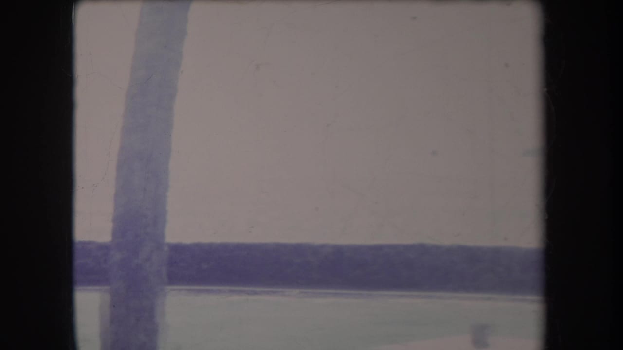 Bright water and distant shore behind dark vertical and horizontal framing elements.
