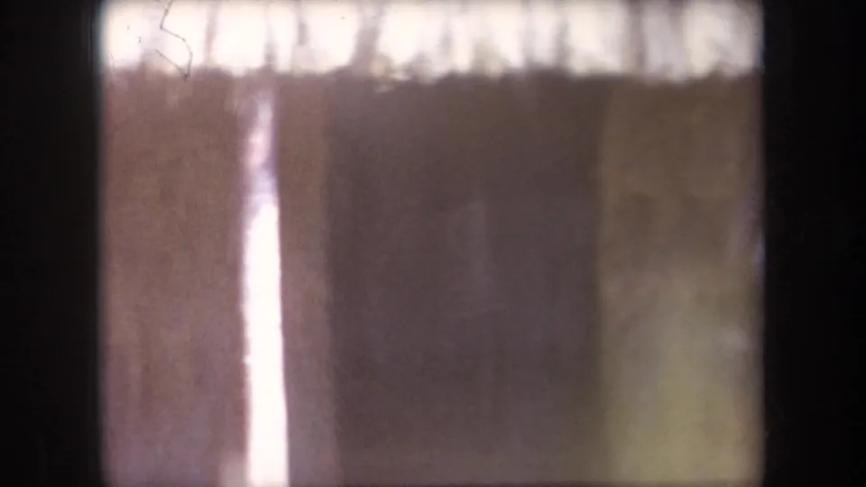 1969 Hawaii home-movie frame with no clear person visible, showing the soft, overexposed hut entrance area and surrounding wall texture.