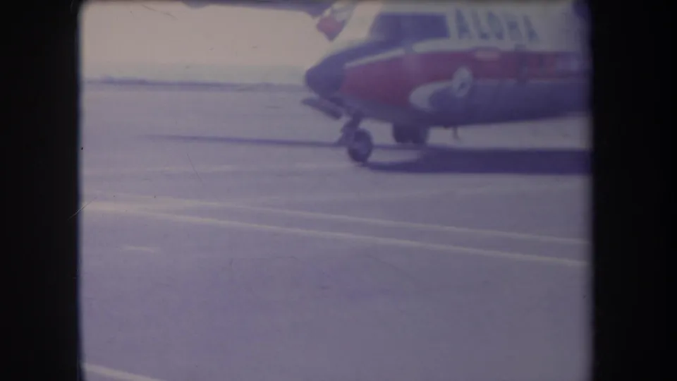 Close cropped 1969 Hawaii airport view with the nose and forward fuselage of a red-and-white aircraft at the edge of the frame.