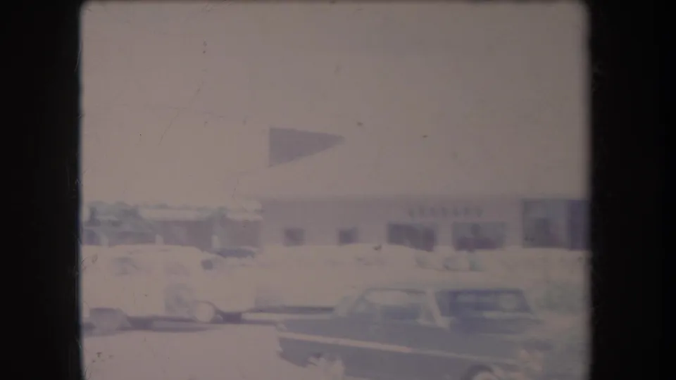 Soft 8mm view of parked classic cars beside a one-story commercial building in Hawaii, dated by metadata to 1969.