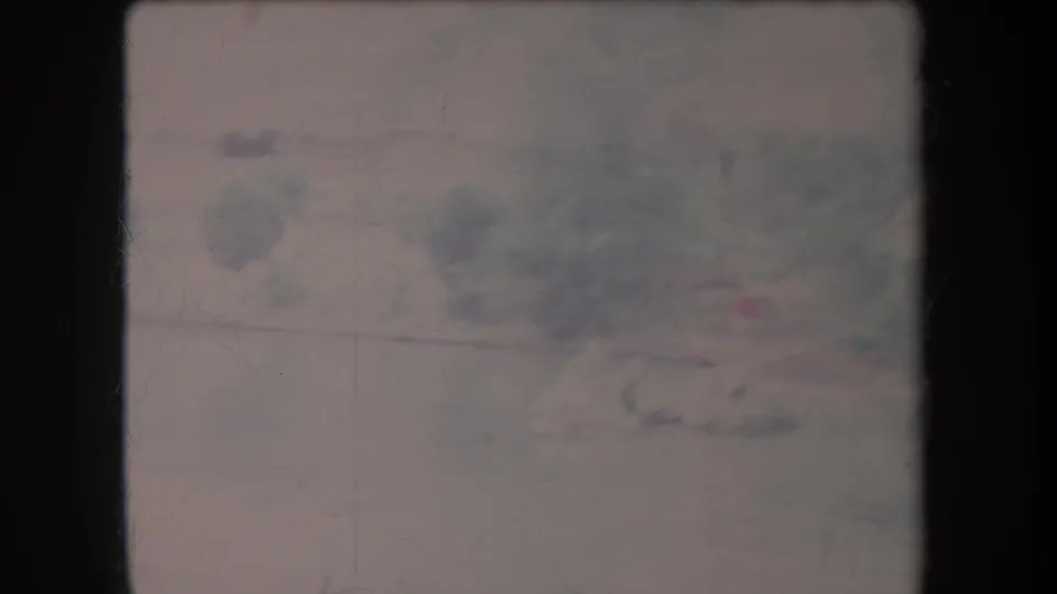 Faded 1969 Hawaii 8mm frame with blurred foliage, pale ground, scratches, and dark film borders.