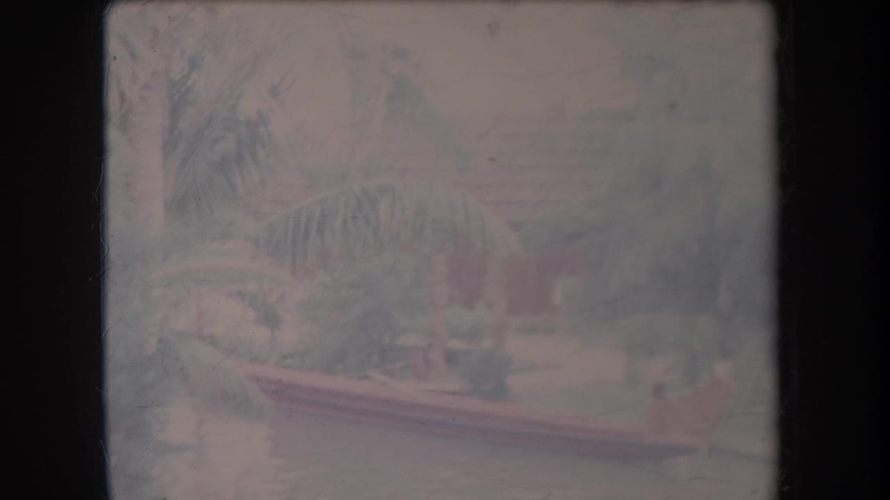 Soft tropical river view with an outrigger canoe near the bank.