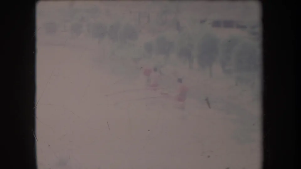1969 Hawaii 8mm frame showing a distant small boat with red-shirted figures on pale, hazy water near trees.