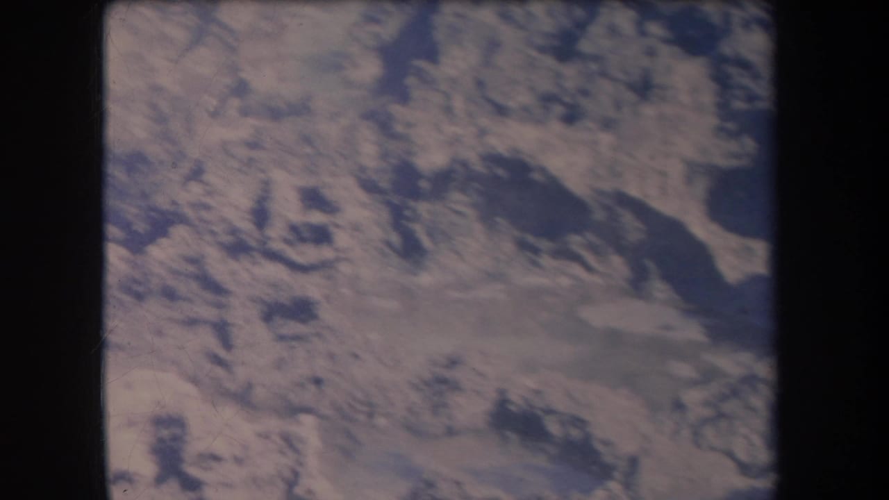 1969 Hawaii aerial home-movie frame with mottled dry terrain, darker irregular patches, and faded 8mm color.