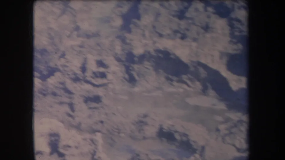 1969 Hawaii aerial home-movie frame with mottled dry terrain, darker irregular patches, and faded 8mm color.