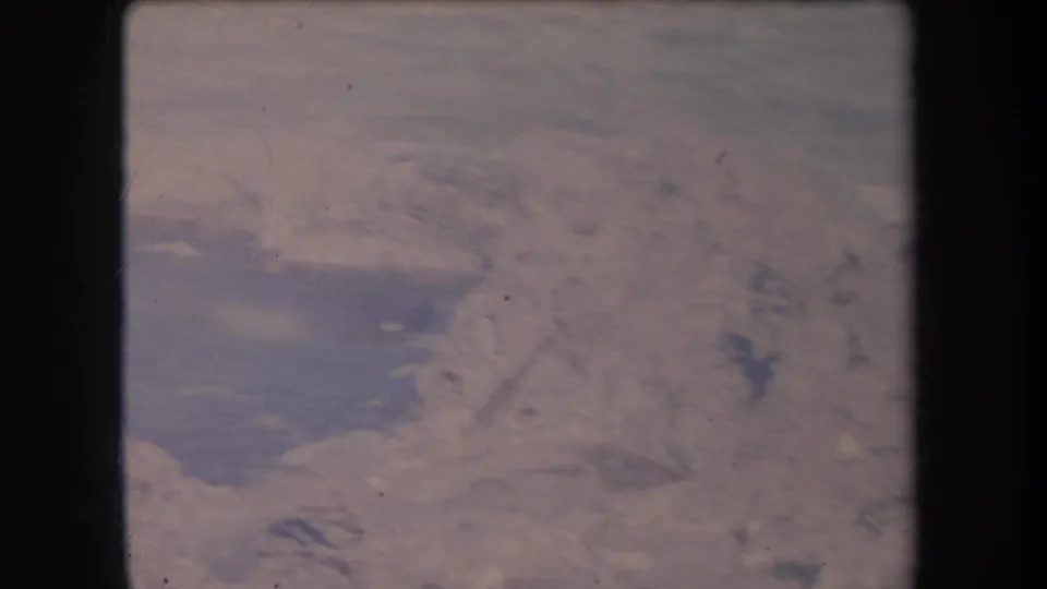 1969 Hawaii shoreline view with white foam and dark rock shapes visible through faded 8mm color.