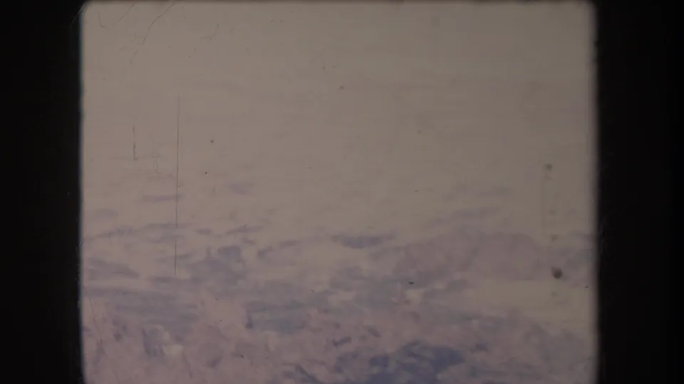 Final 1969 Hawaii 8mm frame showing pale water and dark rocky patterns along a surf-washed coast.