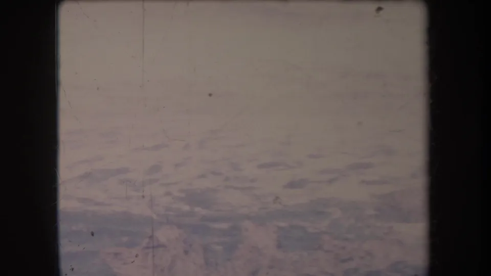 1969 Hawaii 8mm frame showing a hazy aerial view over blue ocean or coastal water with visible film borders and scratches.