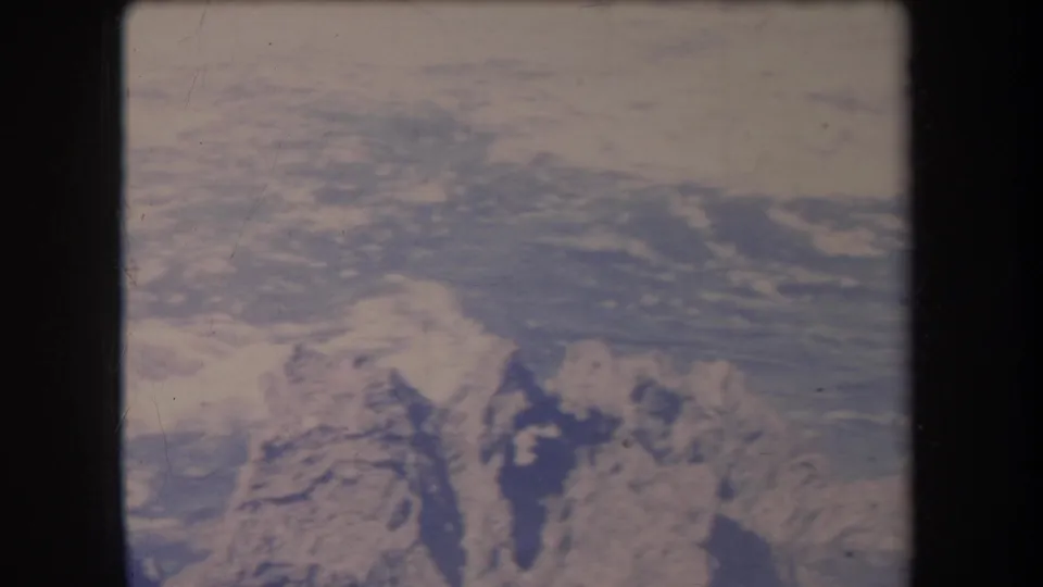 1969 Hawaii 8mm frame with an aerial view of blue water and possible coastal landforms, softened by age and exposure.