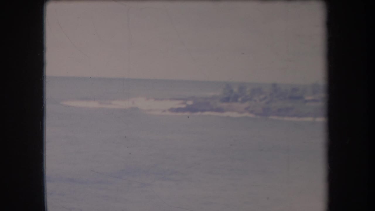 Open water and a hazy shoreline with trees and low buildings in the distance.