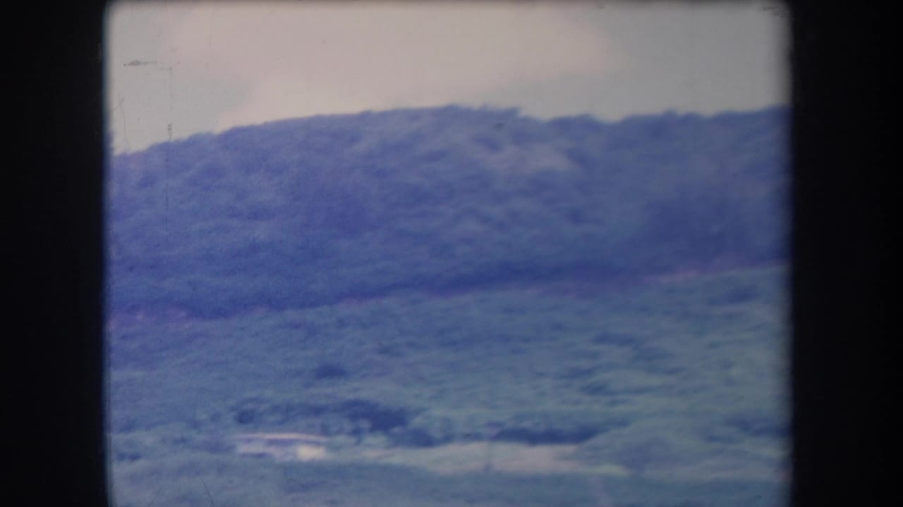 Rolling green hillside and valley area seen through the film frame.