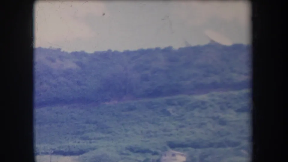 1969 Hawaii 8mm still showing a soft, blue-tinted hillside with layered greenery and slight frame wear.