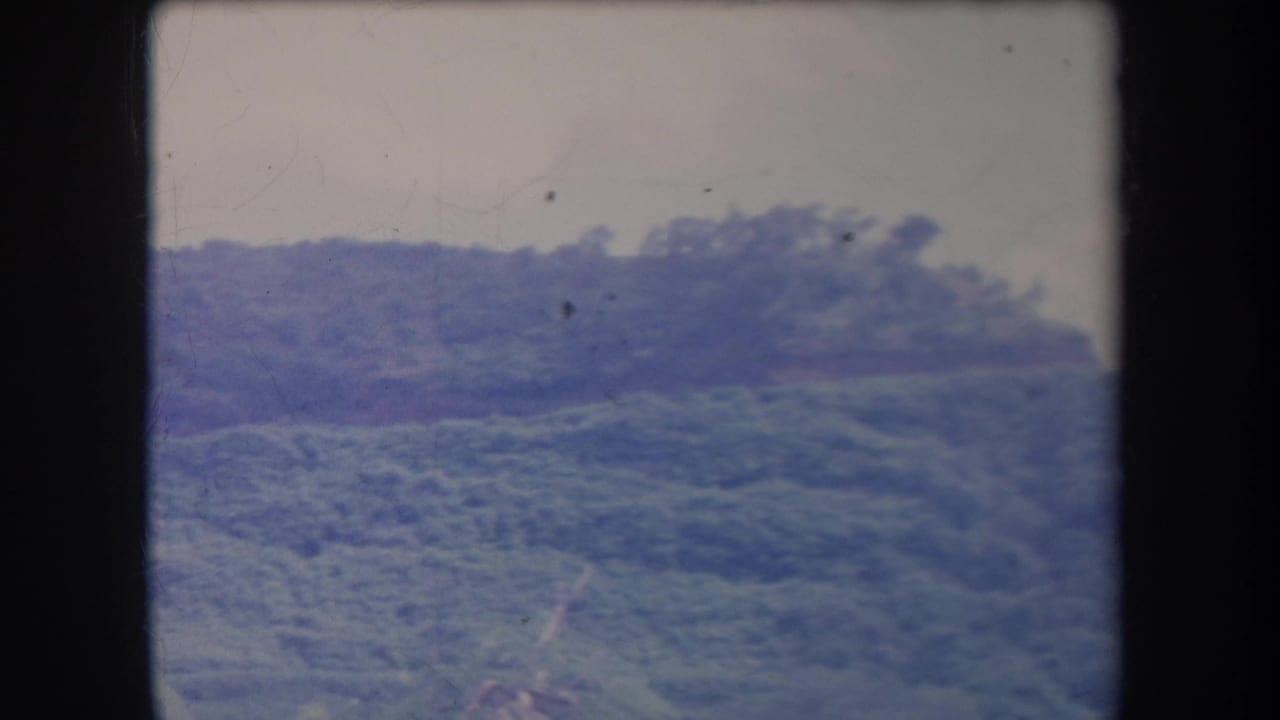 1969 Hawaii frame showing rolling tropical vegetation on a distant ridge, recorded in soft consumer 8mm color.