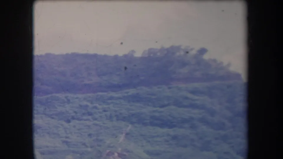 1969 Hawaii frame showing rolling tropical vegetation on a distant ridge, recorded in soft consumer 8mm color.