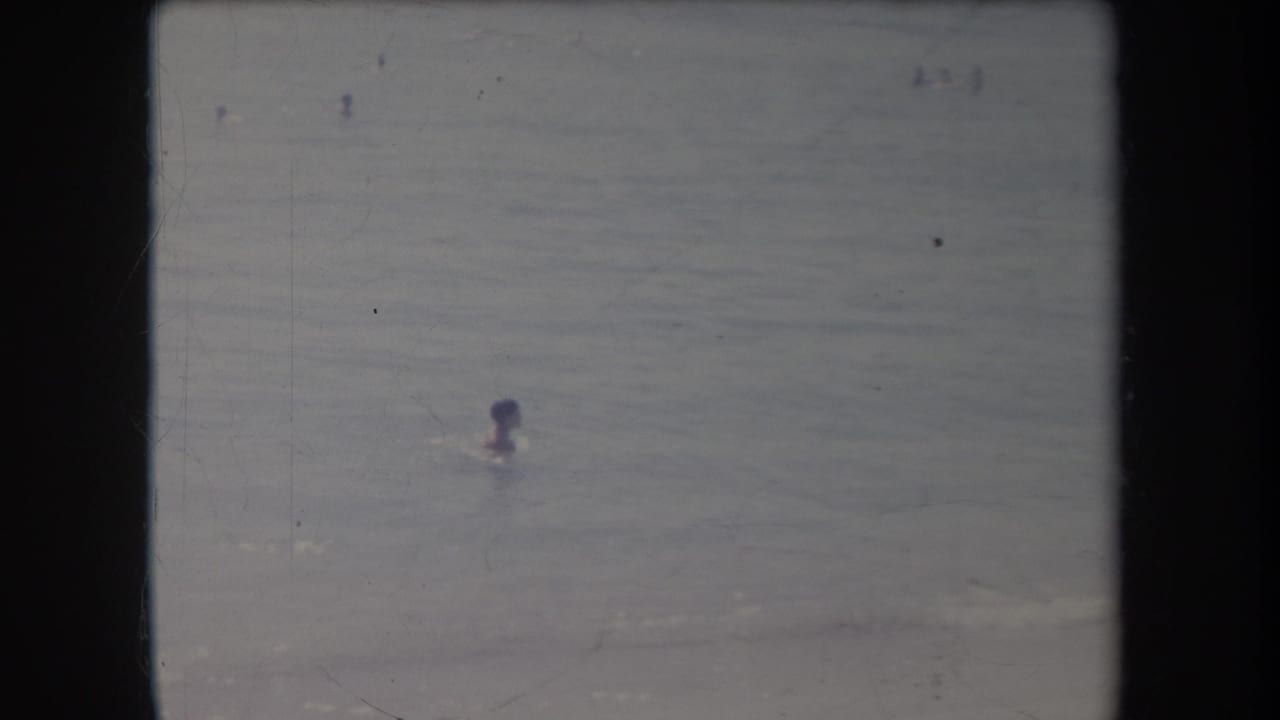 1969 Hawaii 8mm frame showing a distant swimmer in the ocean with soft focus and faded color.