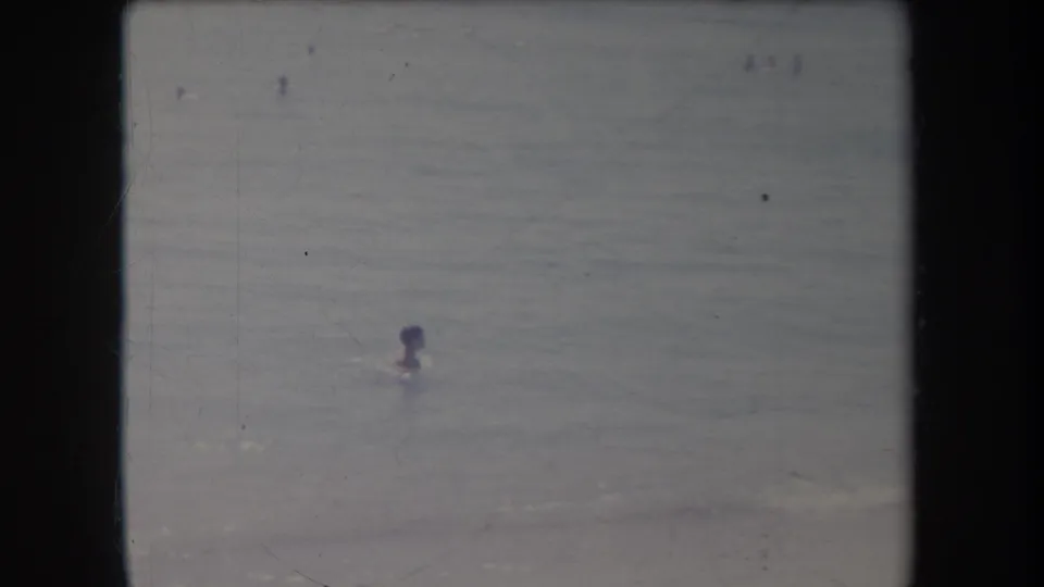 1969 Hawaii 8mm frame showing a distant swimmer in the ocean with soft focus and faded color.