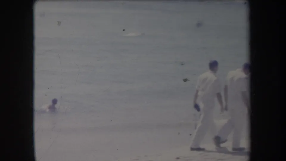 1969 Hawaii 8mm frame with shoreline walkers at the right edge and a swimmer in the surf.