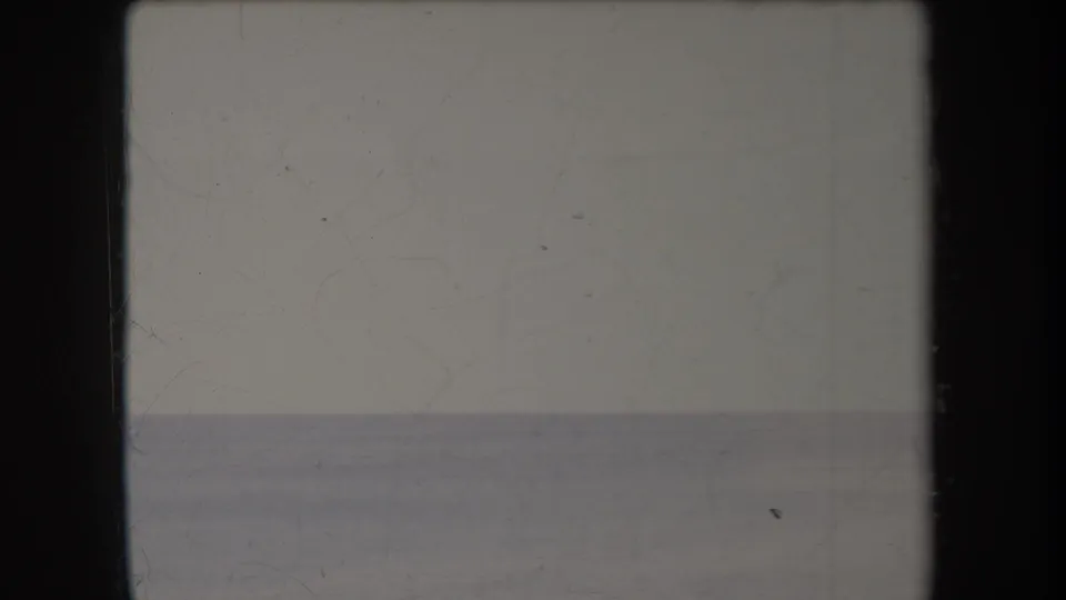 Faded 1969 Hawaii 8mm frame of calm open ocean and pale sky, with the sailboat no longer clearly visible and film wear present.