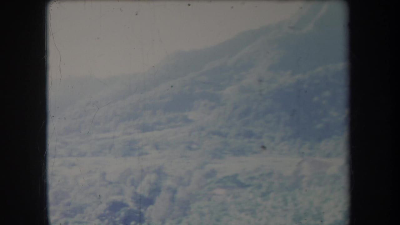 1969 Hawaii 8mm frame showing a hazy shrub-covered mountain ridge beneath an overcast sky.