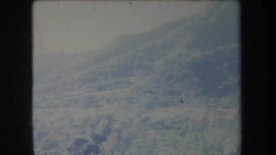 1969 Hawaii 8mm frame showing a hazy shrub-covered mountain ridge beneath an overcast sky.