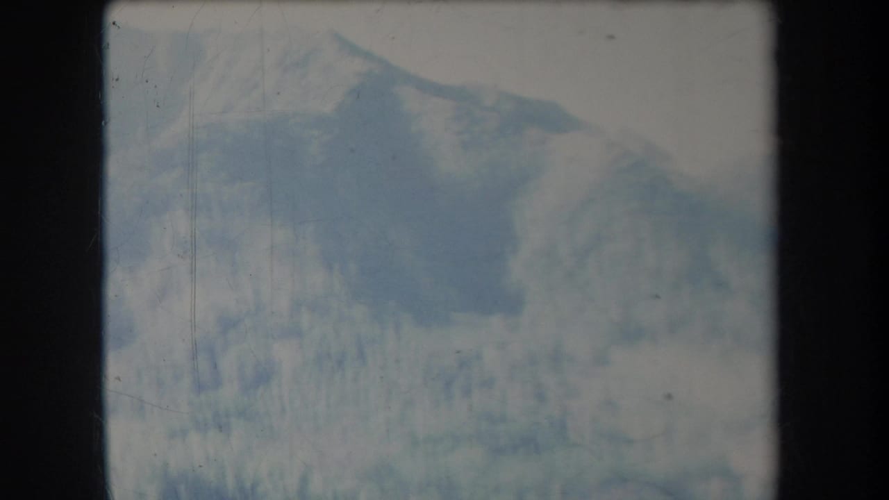 Soft view of hazy forested mountains within a dark film frame.