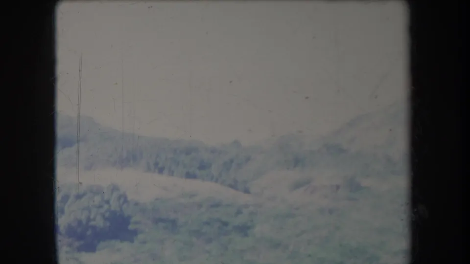 Faded 1969 Hawaii landscape frame with green ridges, open pasture, and muted clouded sky.