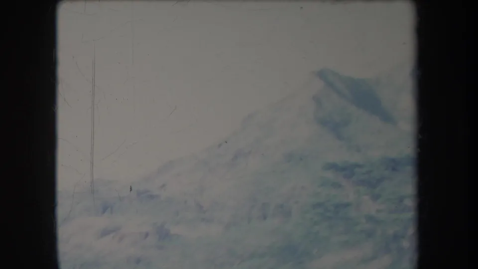 Faded 1969 Hawaii 8mm frame showing a broad mountain slope rising beyond green foreground hills.