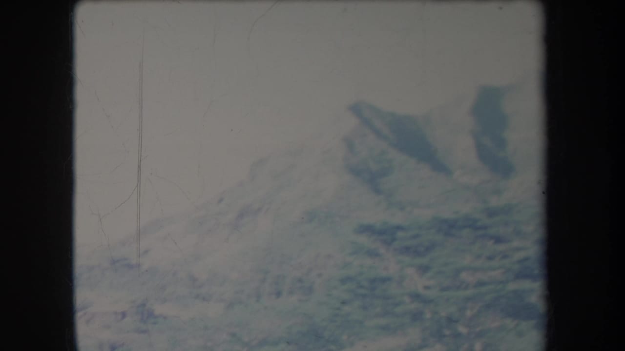 1969 Hawaii 8mm frame showing distant mountain peaks and valley slopes in soft, faded color.