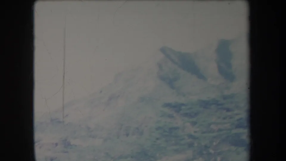 1969 Hawaii 8mm frame showing distant mountain peaks and valley slopes in soft, faded color.