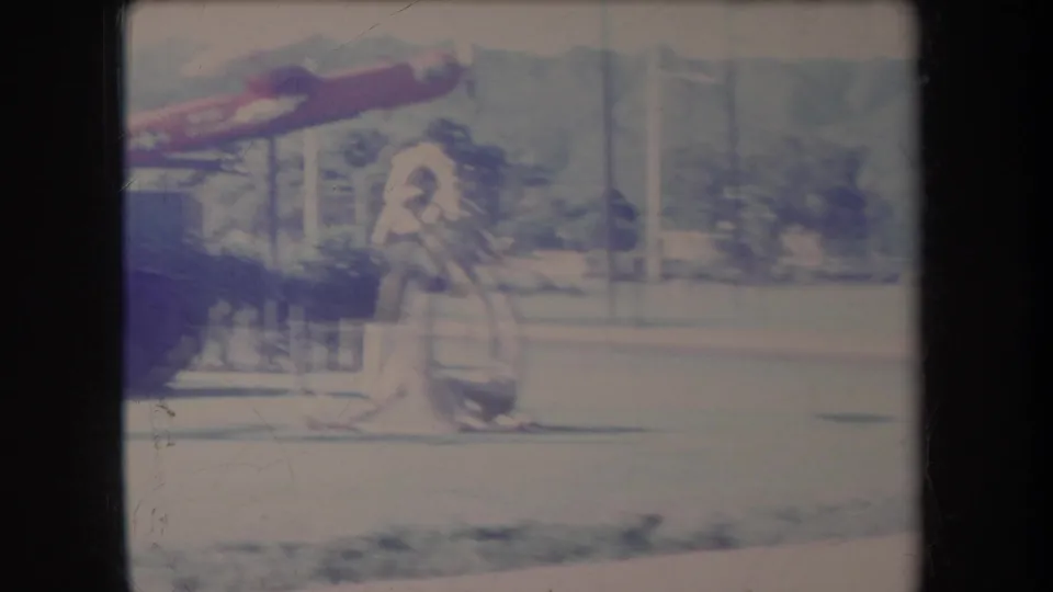 1969 Hawaii home-movie frame showing a red aircraft model above a white figure sculpture in a park-like military display.