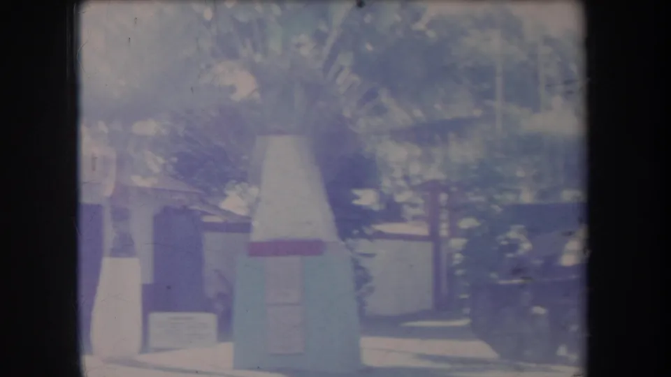 Faded 1969 Hawaii frame with a cone-shaped display or marker, roadside trees, and a car at the edge of the scene.