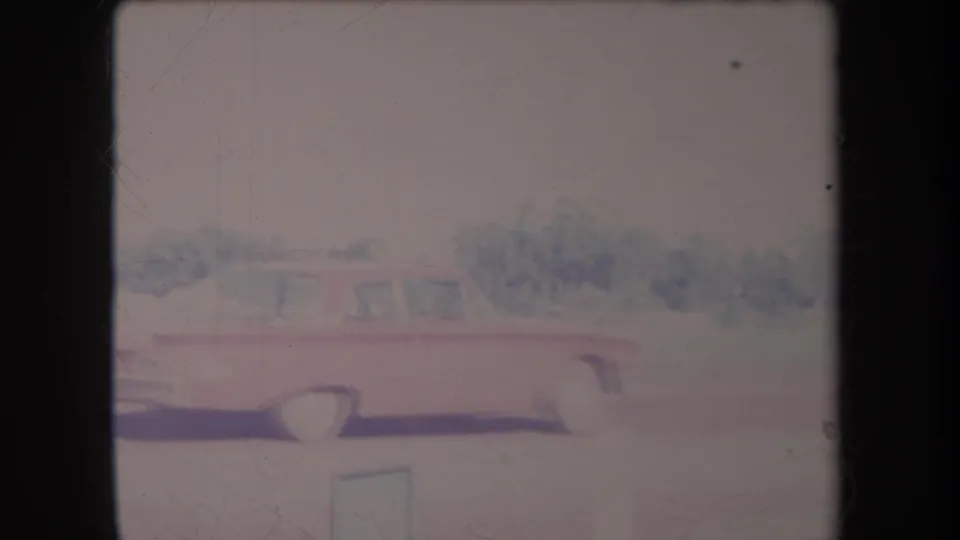 1969 Hawaii 8mm frame showing a red sedan parked on a driveway with dense greenery behind it.