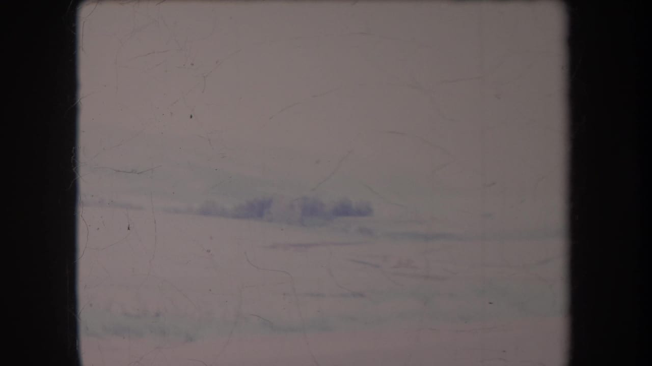 1969 Hawaii home-movie frame with a faint distant ridge and overcast sky, softened by haze, grain, and aged color.