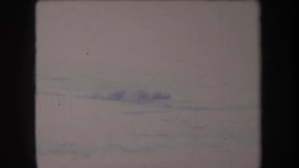 1969 Hawaii home-movie frame with a faint distant ridge and overcast sky, softened by haze, grain, and aged color.
