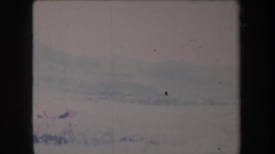 1969 Hawaii 8mm frame showing a pale hazy landscape, distant ridge, foreground grass, and worn film edges.