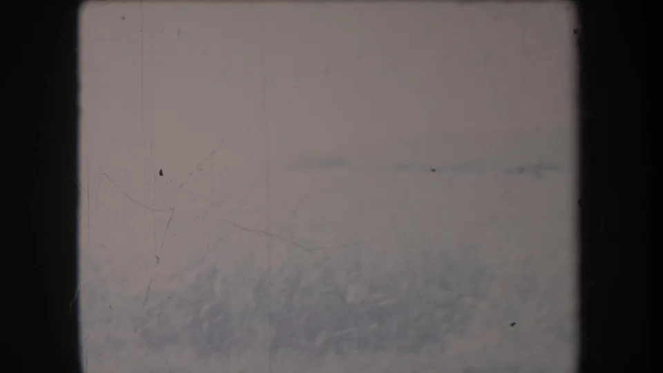 1969 Hawaii 8mm frame with a washed-out field, faint distant horizon, and blurred grass along the lower edge.
