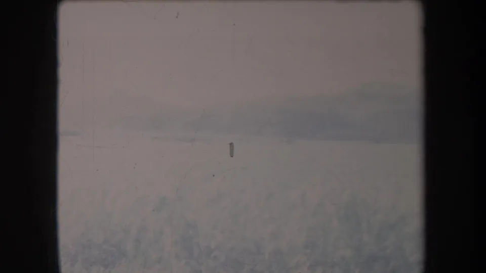 1969 Hawaii 8mm view of a grassy field or valley floor with hazy hills in the background.