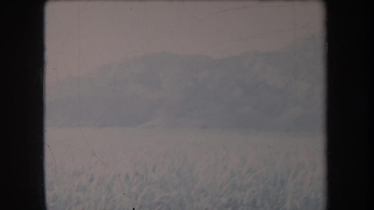 1969 Hawaii 8mm frame showing a snowy foreground and soft distant mountain ridge beneath a muted sky.