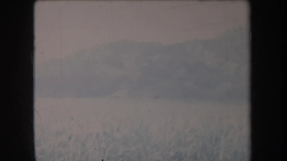 1969 Hawaii 8mm frame showing a snowy foreground and soft distant mountain ridge beneath a muted sky.